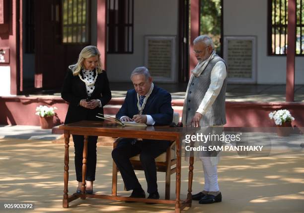 Israeli Prime Minister Benjamin Netanyahu , signs a visitors book as his wife Sara Netanyahu and Indian Prime Minister Narendra Modi look on during a...