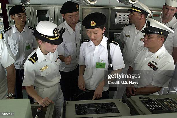 Lieutenant Junior Grade Weihua Hu, center, of the People's Liberation Army Navy shows Ensign Kathleen Merkle, left front, of the guided missile...