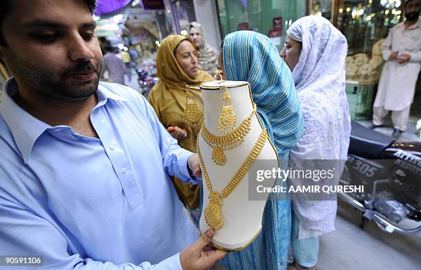 Pakistani man poses with a necklace outside his gold workshop in Rawalpindi on September 9, 2009. Gold prices in Pakistan on September 9 touched a...