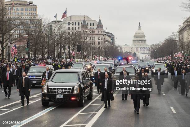 Members of the secret service walk next to the limousine carrying U.S. President Donald Trump and First Lady Melania Trump drives in the 58th...