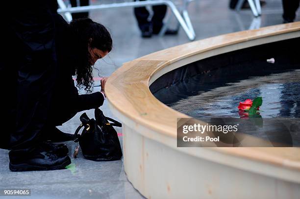 Woman writes a message as family members visit the reflecting pool to pay their respects at Ground Zero during a 9/11 memorial ceremony on September...