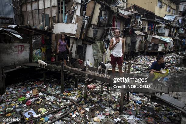 Residents rest on a wooden bridge over a garbage-filled waterway in Manila on January 17, 2018. / AFP PHOTO / NOEL CELIS