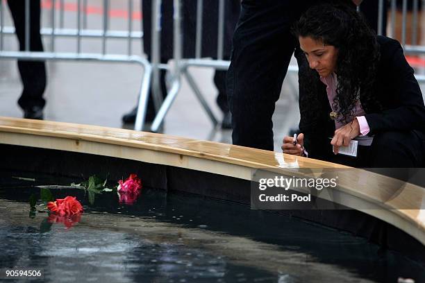 Woman writes a message as family members visit the reflecting pool to pay their respects at Ground Zero during a 9/11 memorial ceremony on September...