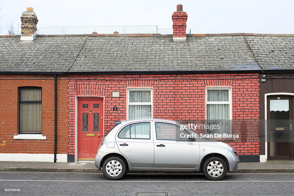 Silver compact car parked outside brick home