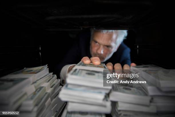 pov man taking stacks of us dollars from a hiding place - andy andrews stock-fotos und bilder