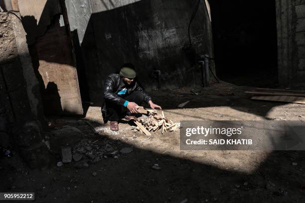 Palestinian man chops wood in the Rafah refugee camp in the southern Gaza Strip on January 17, 2018. The UN agency for Palestinian refugees faces its...