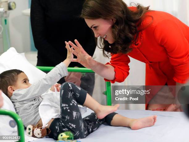 Catherine, Duchess of Cambridge reacts to patient Rafael Chana as she visits Great Ormond Street Hospital to officially open the Mittal Children's...