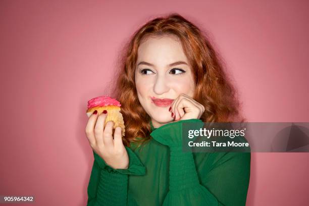 woman eating cup cake - woman holding cake stock-fotos und bilder