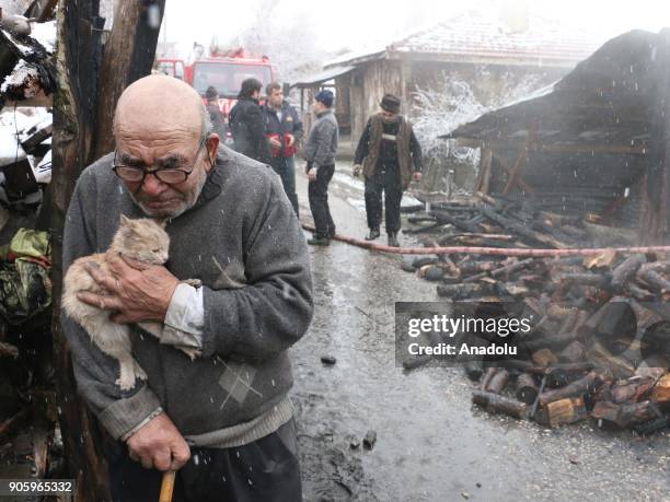 Year-old Ali Mese carries a cat saved from a fire by firefighters during snowfall as firefighters try to extinguish the fire broken out at old man's...