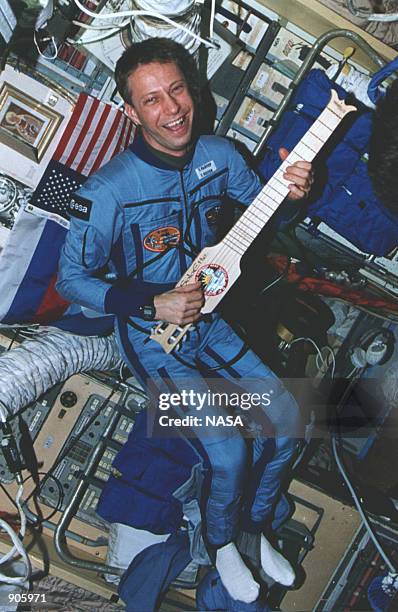In Mir's core module, the European Space Agency's Thomas Reiter tests a collapsible guitar which was a gift for the Mir from the STS-74 crew in March...