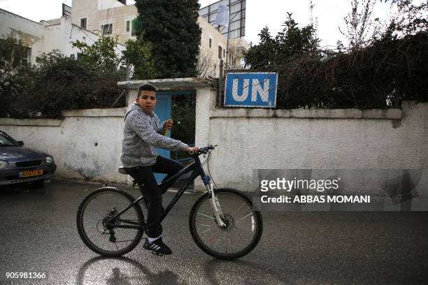 Palestinian boy cycles past a United Nations' run health centre in the Qalandia refugee camp near Ramallah in the West Bank, on January 17, 2018...