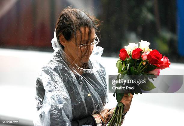 Woman carries flowers as she walks to the reflecting pool as people gather at Ground Zero during a 9/11 memorial ceremony on September 11, 2009 in...