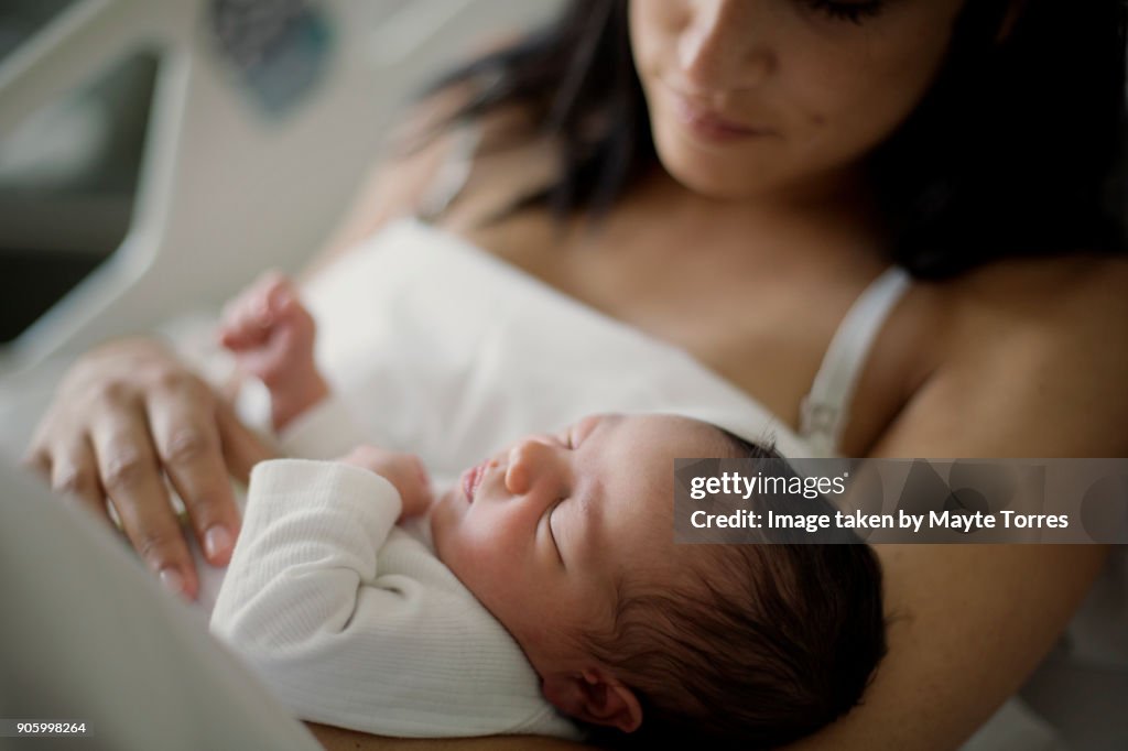 Close up of newborn girl with mom at bed in hospital