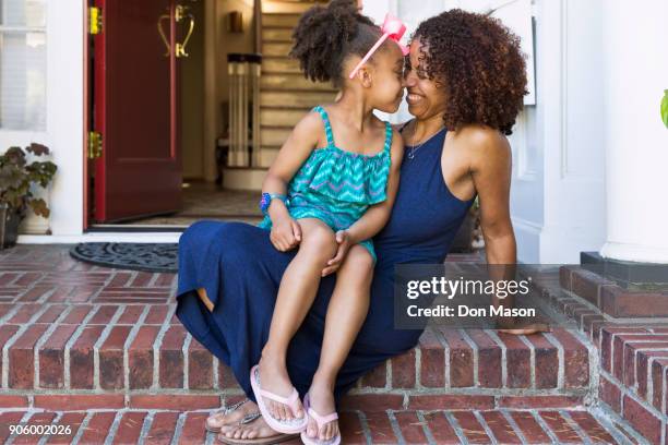 smiling mixed race mother and daughter rubbing noses on front stoop - minority groups ストックフォトと画像