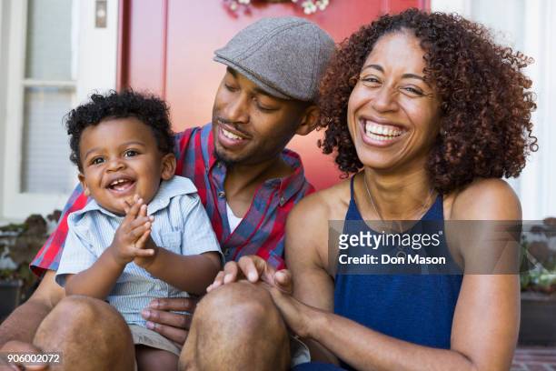 laughing mixed race couple sitting on front stoop with son - adult baby women stock pictures, royalty-free photos & images