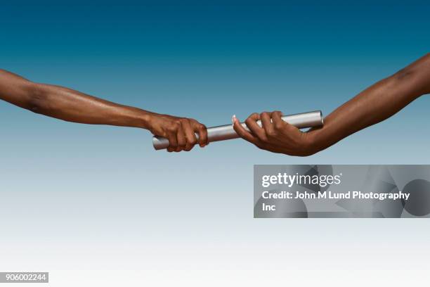hands of women passing baton on blue background - stafettpinne bildbanksfoton och bilder