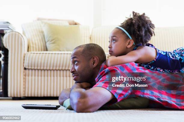 mixed race father and daughter laying on floor watching television - lying on back ストックフォトと画像