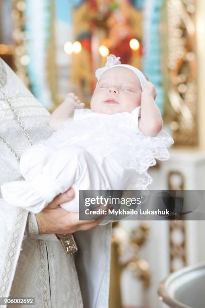 priest holding baby girl in church - priest baptism stock pictures, royalty-free photos & images