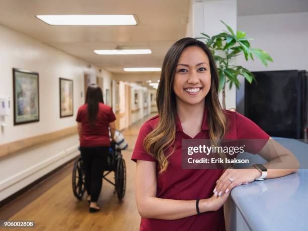 portrait of smiling nurse leaning on counter in hospital - physical therapist stock pictures, royalty-free photos & images