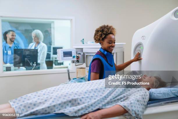 smiling technician preparing scanner for patient - radioloog stockfoto's en -beelden