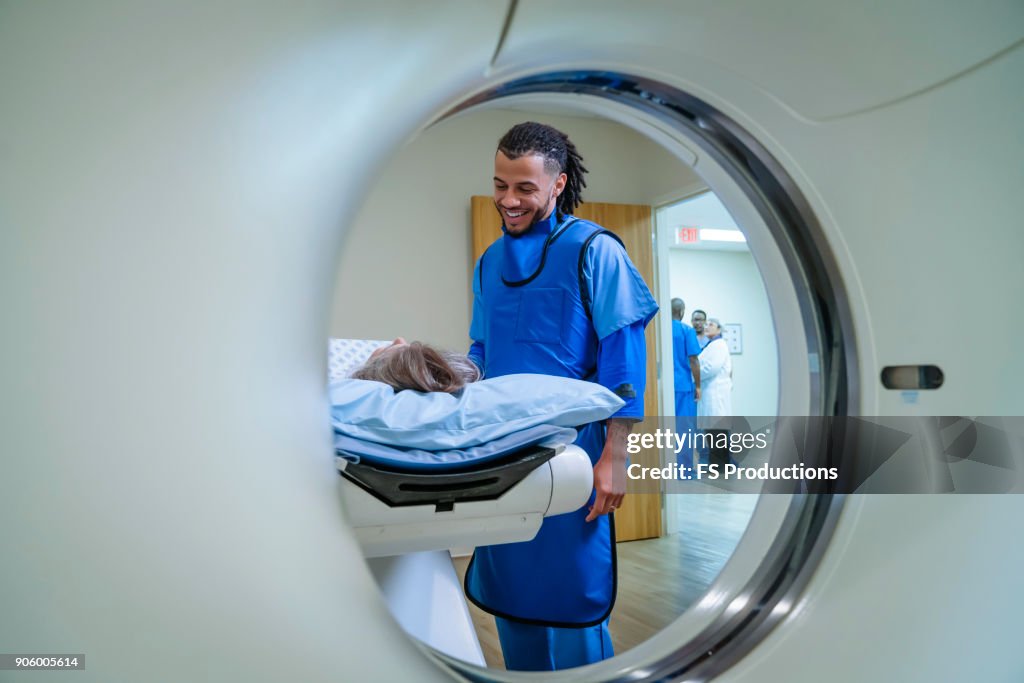 Technician talking to patient near scanner