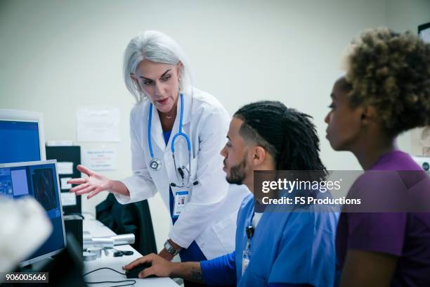 doctor talking to nurses at computer - radiographer stock pictures, royalty-free photos & images