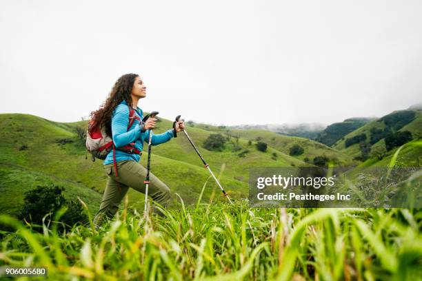 smiling mixed race woman hiking with walking sticks - hiking pole stock pictures, royalty-free photos & images