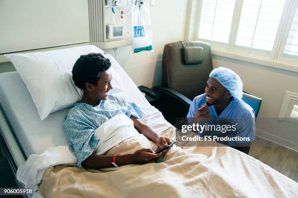 black nurse talking to boy in hospital bed - bedside manner stock pictures, royalty-free photos & images