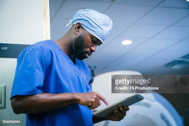 serious black nurse using digital tablet - tablet close up real copyspace stock pictures, royalty-free photos & images