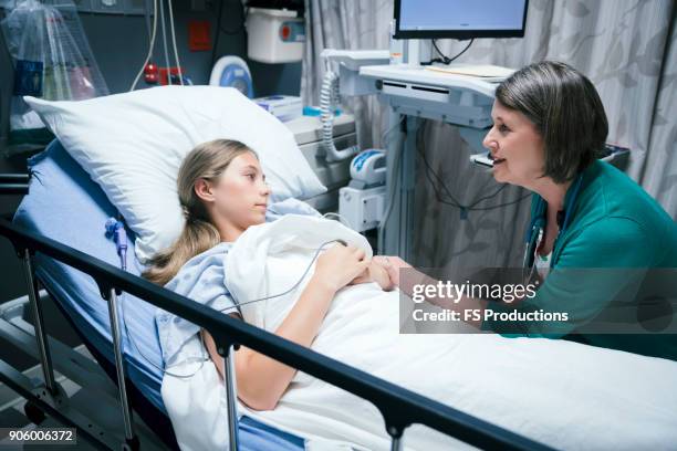 caucasian doctor comforting patient in hospital bed - sad child hospital stock pictures, royalty-free photos & images