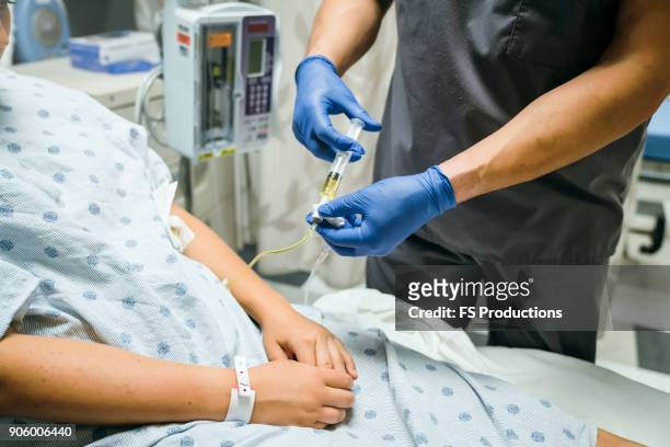 nurse injecting medicine into tube of patient - iv infuus stockfoto's en -beelden