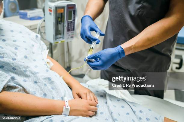 nurse injecting medicine into tube of patient - hospital bed with iv stock pictures, royalty-free photos & images