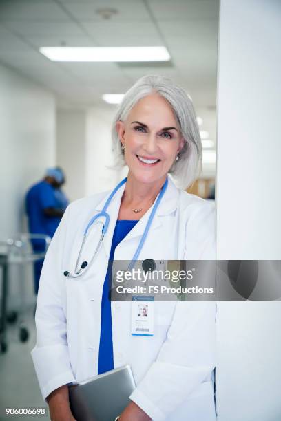 portrait of caucasian doctor leaning on wall in hospital - tablet close up real copyspace stock pictures, royalty-free photos & images