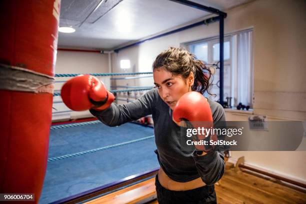 femelle boxer poinçonnant un sac de poinçon - boxe femme photos et images de collection