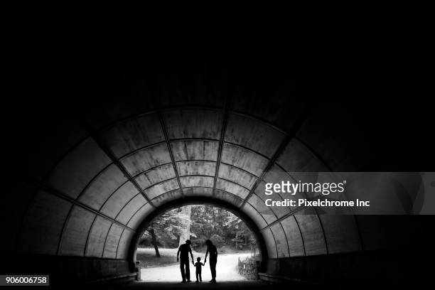 distant couple in tunnel holding hands with son - pixelchrome inc stock pictures, royalty-free photos & images