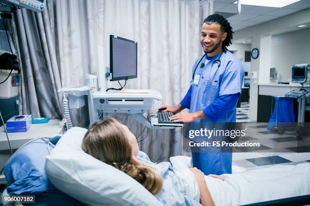 nurse talking to patient in hospital bed - krankenbett gespräch stock-fotos und bilder