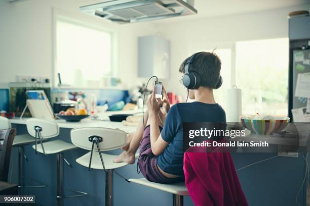 mixed race boy sitting in kitchen listening to cell phone - boy ipod stock pictures, royalty-free photos & images