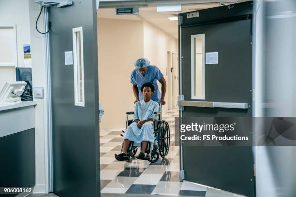 black nurse pushing boy in wheelchair - entering hospital stock pictures, royalty-free photos & images