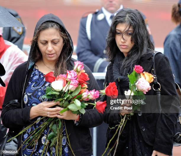 Women hold roses as they walk to pay their respects at Ground Zero during a 9/11 memorial ceremony on September 11, 2009 in New York City. Family of...