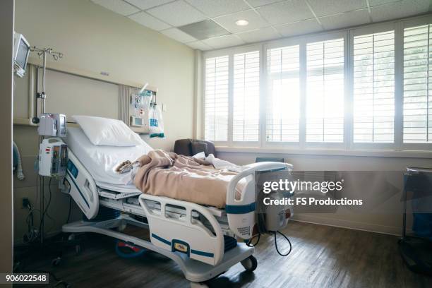 empty hospital bed near sunny window - hospital bed stockfoto's en -beelden