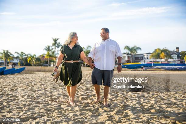 senior mexican couple walking at the beach - fat couple stock pictures, royalty-free photos & images