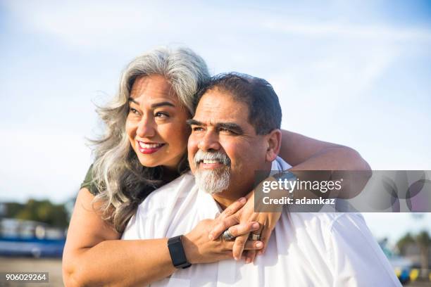 senior mexican couple piggyback at the beach - contemplation couple stock pictures, royalty-free photos & images