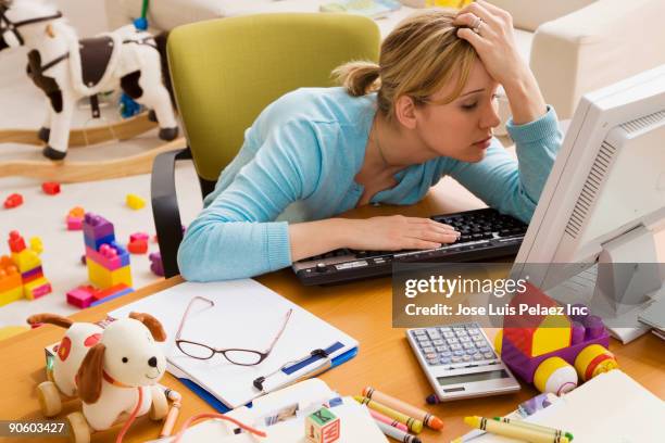 frustrated hispanic woman at desk surrounded by toys - overworked computer stock pictures, royalty-free photos & images