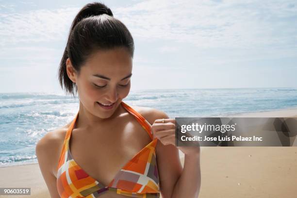 mixed race woman checking bikini tan lines on beach - marque de bronzage photos et images de collection