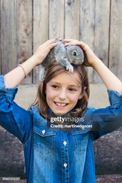 nettes mädchen mit einem baby-kaninchen auf dem kopf im freien im frühjahr. - diastema stock-fotos und bilder