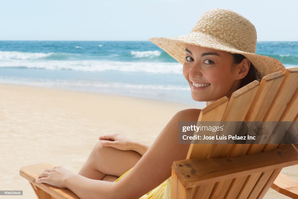 Mixed race woman relaxing in chair on beach