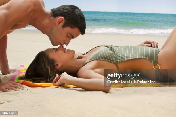 man kissing woman laying on beach - chest kissing stockfoto's en -beelden