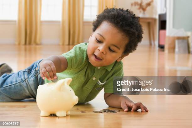 african toddler putting money in piggy bank - save our future babies stock pictures, royalty-free photos & images