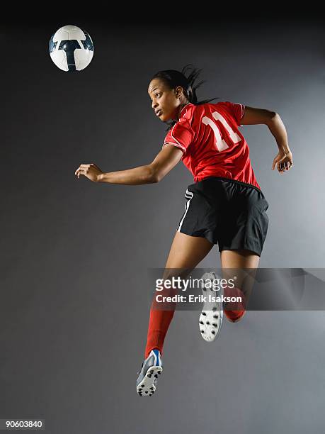 mixed race soccer player in air with soccer ball - mixed race woman stock-fotos und bilder