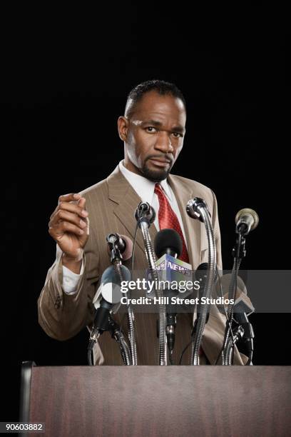 african man standing at podium with microphones - president speech stock pictures, royalty-free photos & images